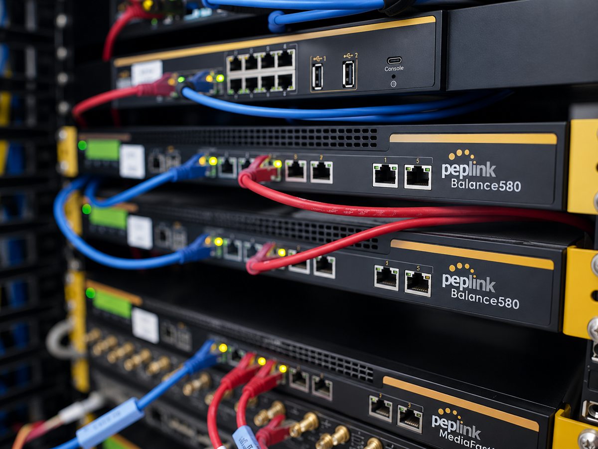 Rack of Peplink Balance routers with patched ethernet cables